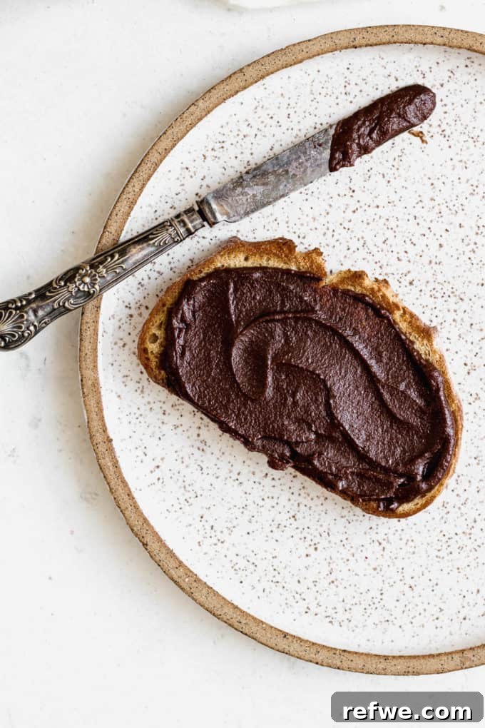 Plant-Based Hazelnut Cacao Dream 14 A piece of toast generously topped with homemade vegan Nutella, with a knife on the side.