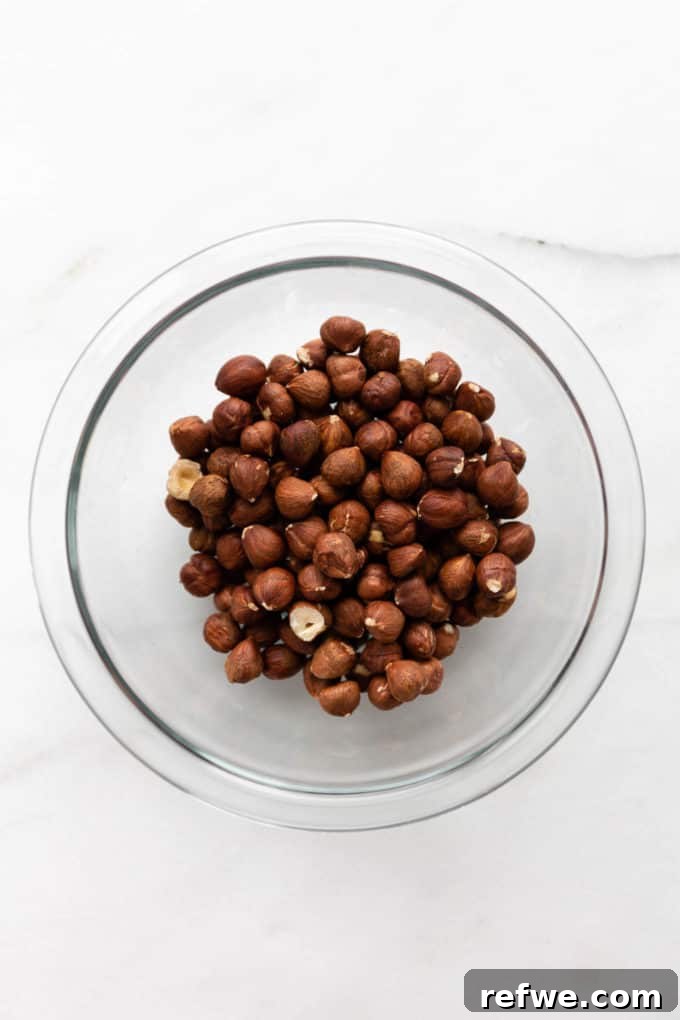 Plant-Based Hazelnut Cacao Dream 3 Raw hazelnuts in a clear bowl before roasting.