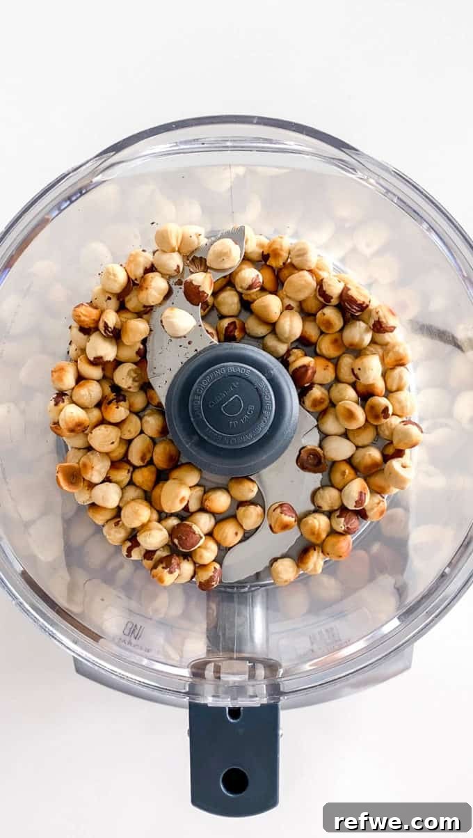 Plant-Based Hazelnut Cacao Dream 7 Hazelnuts being processed in a food processor, forming a coarse powder.