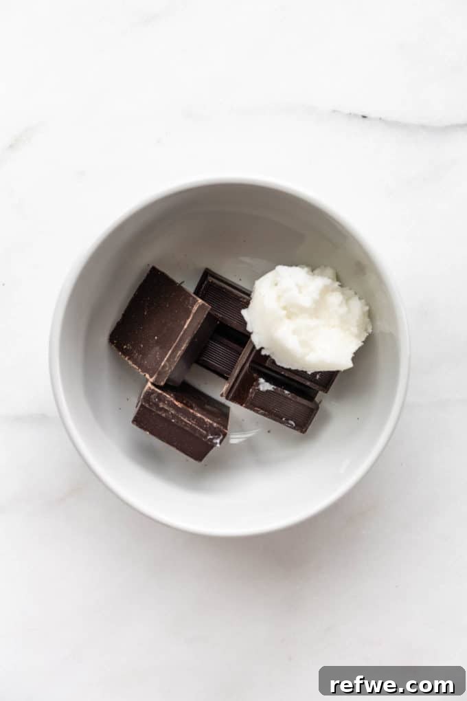Plant-Based Hazelnut Cacao Dream 9 Dark chocolate chunks and solid coconut oil in a white bowl before melting.