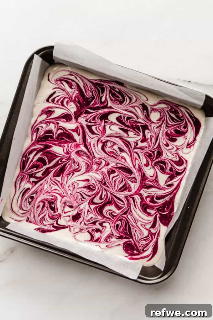 Decadent Vegan Raspberry Cheesecake Bars 11 A baking pan with swirled vegan raspberry cheesecake, showcasing artistic raspberry patterns