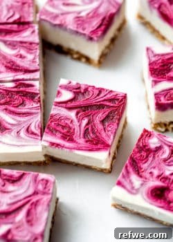 Vegan raspberry cheesecake bars with raspberry swirl on top on them