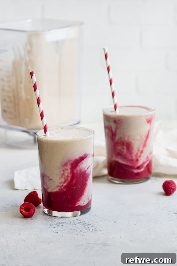 Berry Peanut Butter Bliss 3 A single glass of a beautifully layered peanut butter and jelly smoothie, showing distinct purple and beige sections.