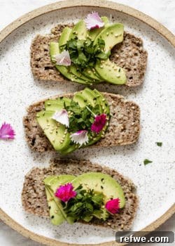 three slices of avocado toast on a plate topped with pink flower petals
