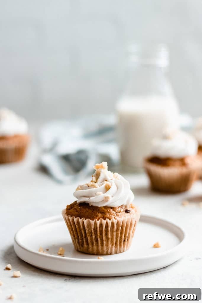 Irresistible Vegan Carrot Cupcakes 6 A single vegan carrot cake cupcake sitting elegantly on a white plate, inviting a moment of pure enjoyment.