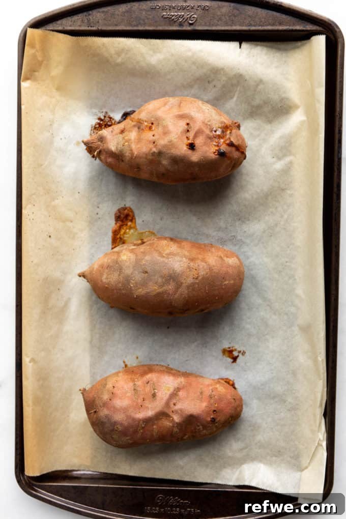 Hearty Black Bean Quinoa Stuffed Sweet Potatoes 4 Perfectly roasted sweet potatoes, tender and slightly browned, resting on a baking sheet straight from the oven.