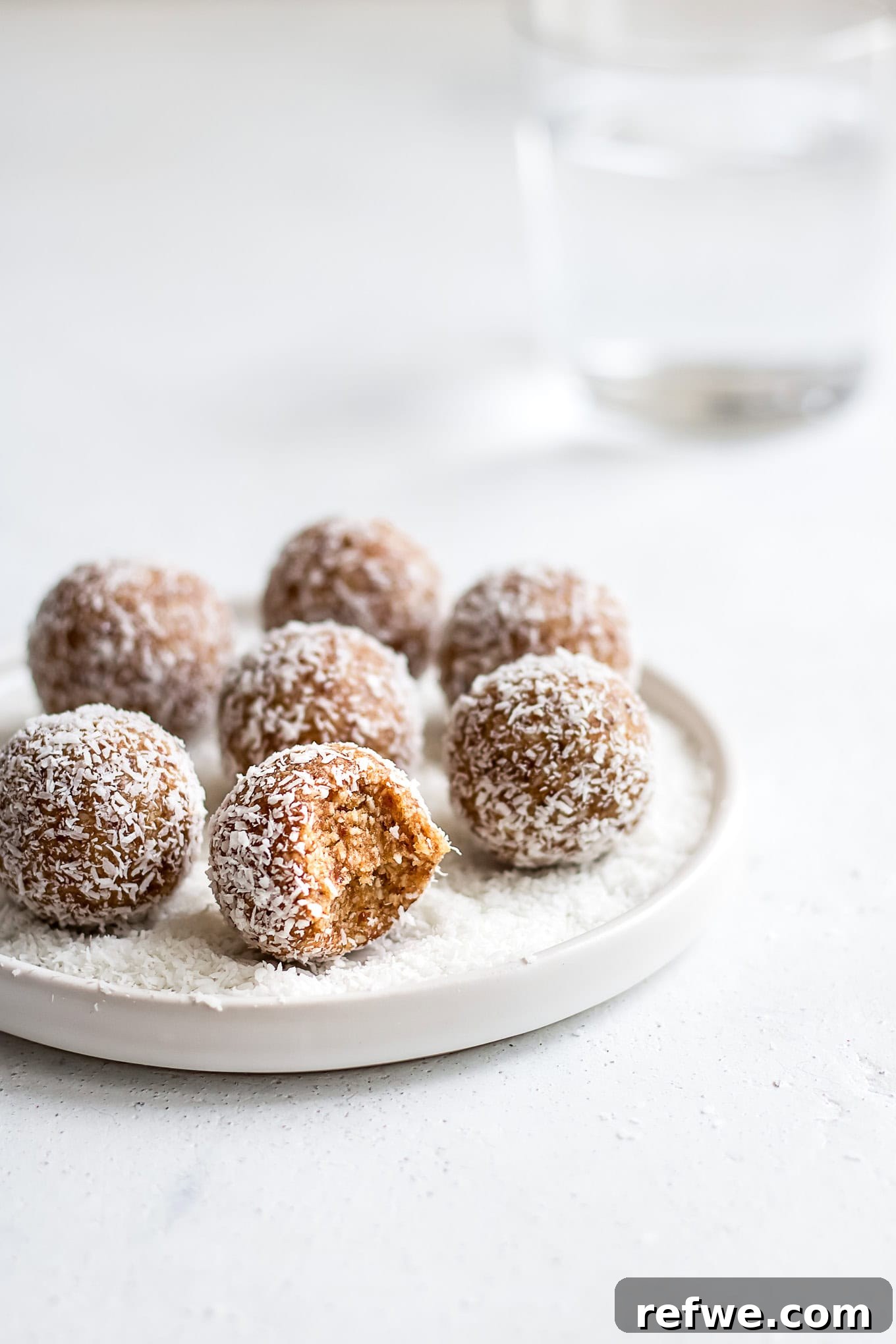 Irresistible Salted Caramel Coconut Bites 2 A vibrant close-up of beautifully rolled salted caramel coconut bliss balls on a pristine white plate, garnished with extra shredded coconut and a hint of sea salt.