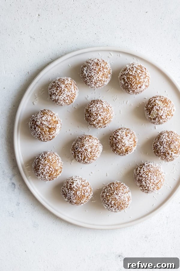 Irresistible Salted Caramel Coconut Bites 5 A close-up of a single salted caramel coconut bliss ball, highlighting its texture and coconut coating against a soft-focus background.