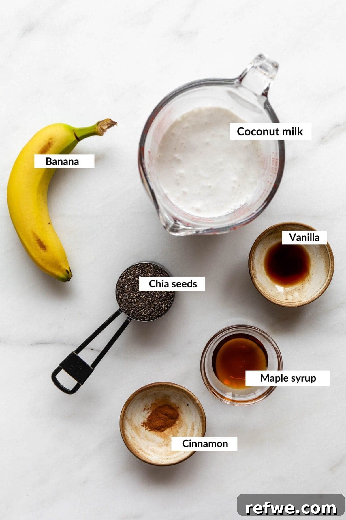 Wholesome Banana Chia Delight 3 A flat lay photograph showcasing the key ingredients for banana chia pudding: fresh ripe bananas, chia seeds, a bottle of coconut milk, maple syrup, and cinnamon.
