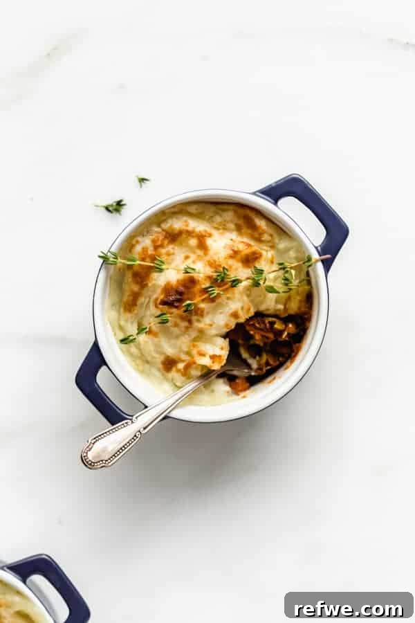 Plant-Powered Lentil Shepherd's Pie 2 A beautifully baked vegan lentil shepherd's pie in a small blue ramekin, with a spoon ready to scoop