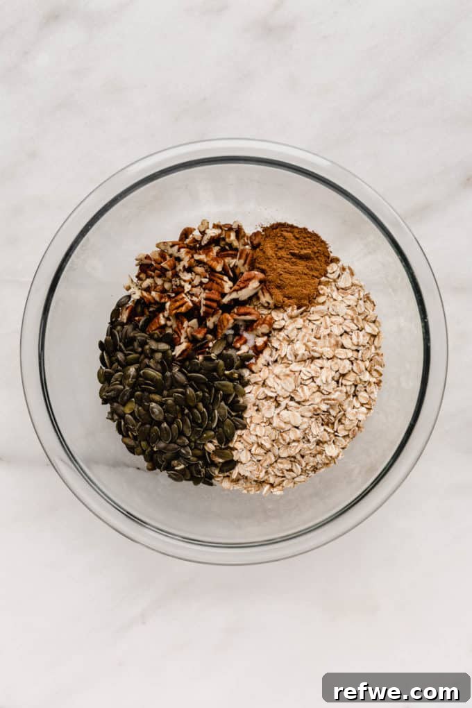 Cozy Autumn Granola 4 A mixing bowl filled with dry ingredients for granola: oats, pumpkin seeds, and pecans.