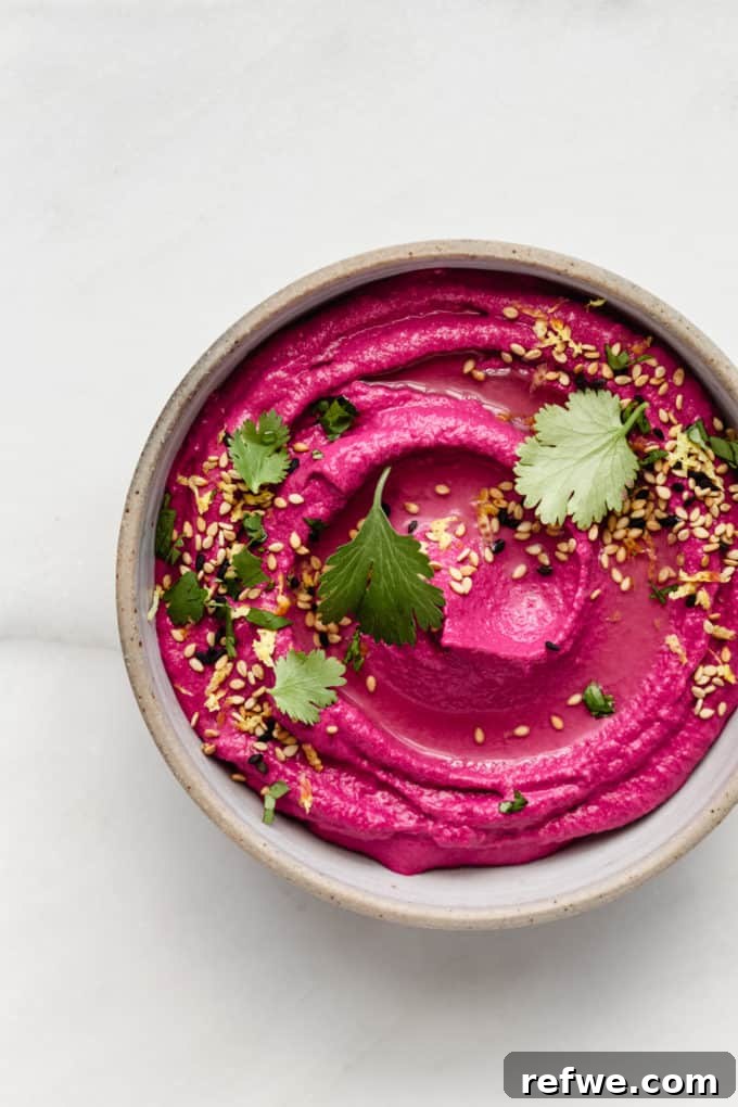 Vibrant Roasted Beet Hummus 2 A bowl of vibrant Roasted Beet Hummus, garnished with fresh cilantro and toasted sesame seeds, ready to be served.