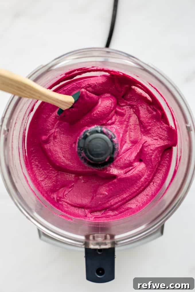Vibrant Roasted Beet Hummus 3 Roasted beet hummus being blended in a food processor, showing its creamy texture and vibrant pink color.