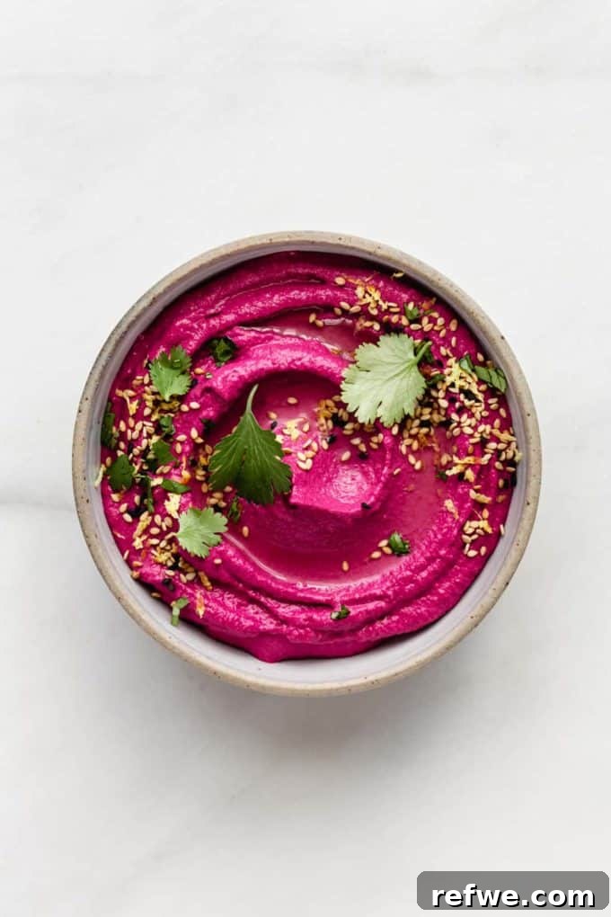Vibrant Roasted Beet Hummus 5 A bowl of roasted beet hummus on a elegant marble countertop, garnished with a sprig of fresh herbs.