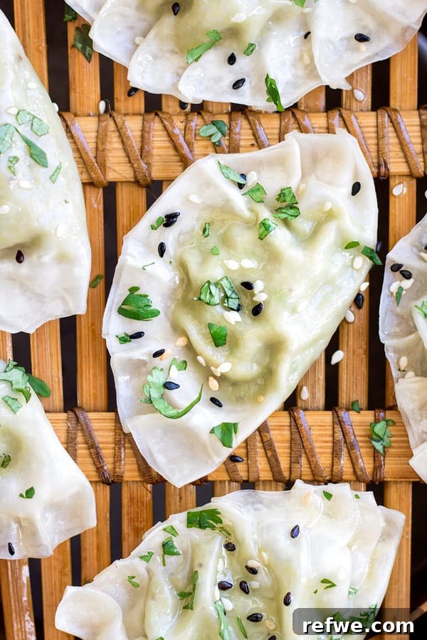 A neatly arranged row of raw Edamame and truffle dumplings, ready for cooking, on a wooden board.
