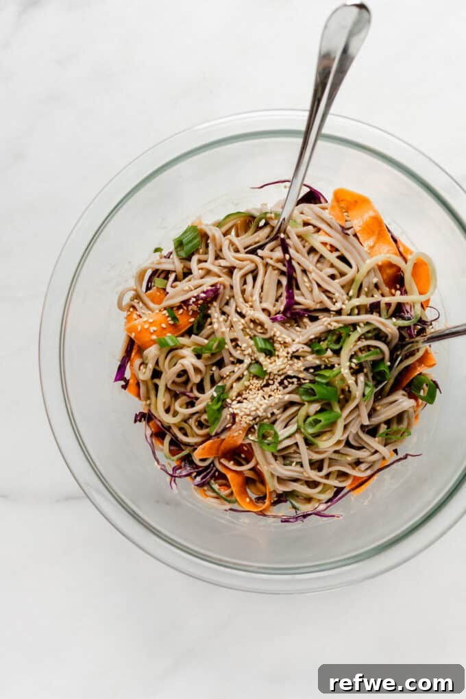 Chilled Soba Noodles with Creamy Peanut Sauce 7 The cold soba noodle salad, mixed with the creamy peanut sauce, in a large mixing bowl, showing the even coating of the dressing on all ingredients.