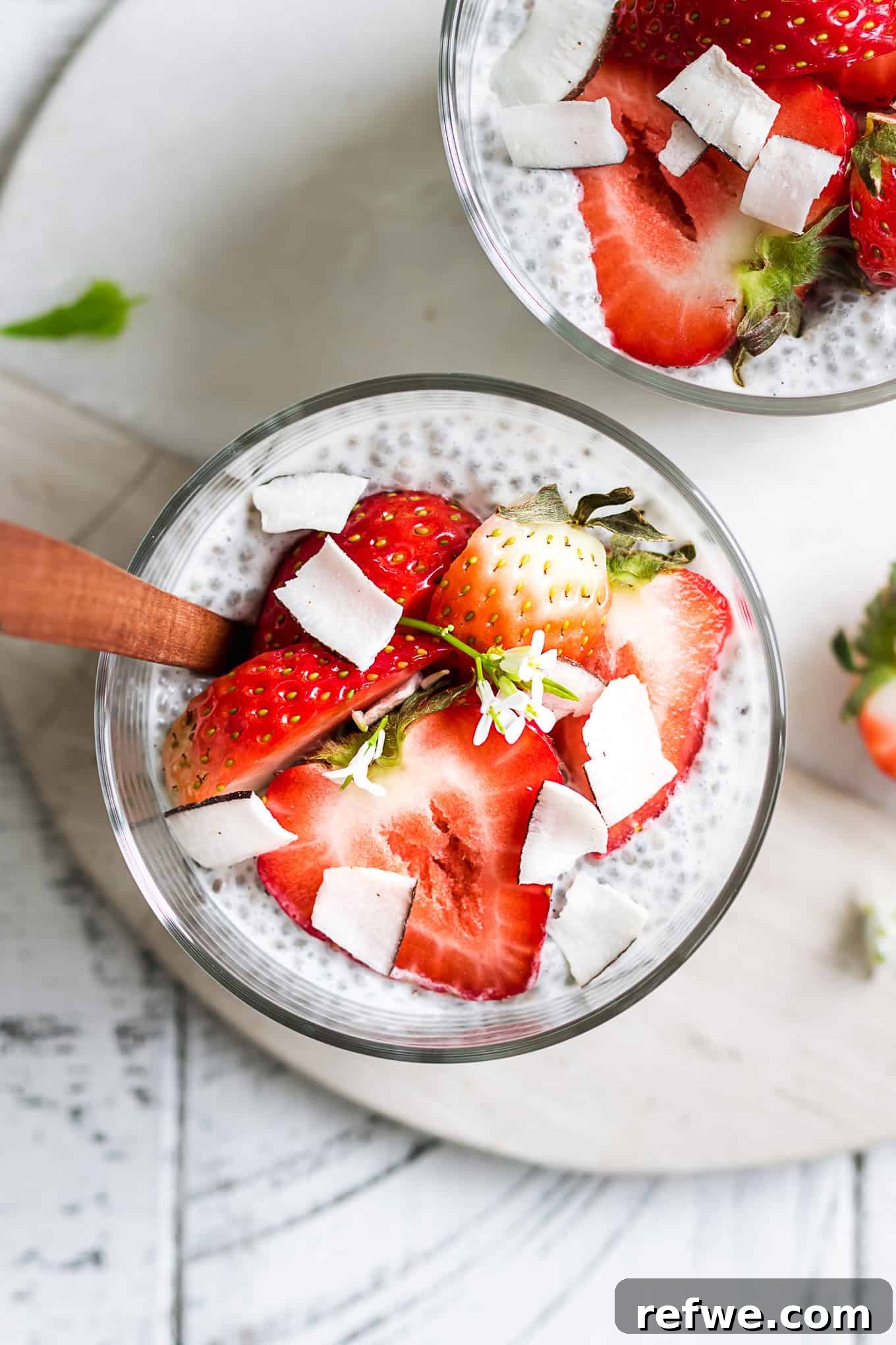 Close-up shot of fresh strawberries perfectly complementing the creamy coconut chia pudding beneath, highlighting fresh toppings.