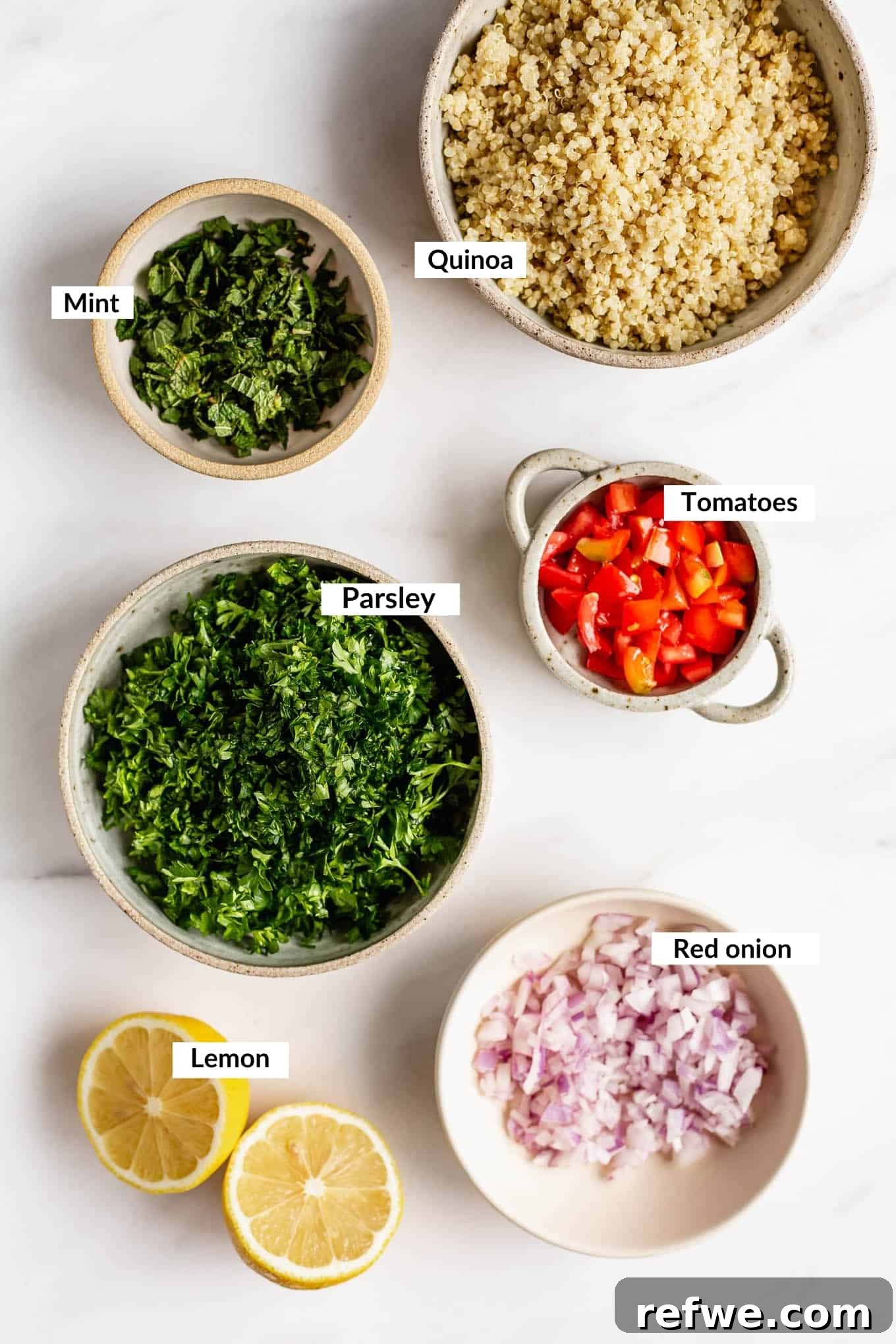 Mediterranean Quinoa Tabbouleh 3 A flat lay photograph showcasing fresh ingredients for quinoa tabbouleh salad: cooked quinoa, finely chopped parsley, mint, cherry tomatoes, and red onion.