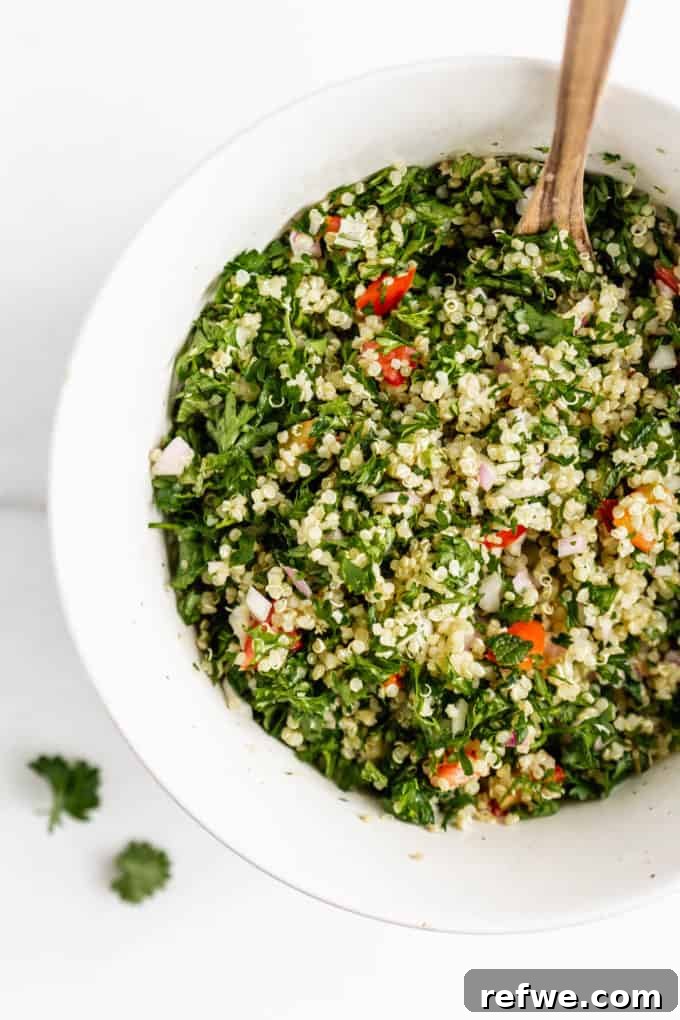 Mediterranean Quinoa Tabbouleh 5 A close-up shot of a bowl of freshly prepared quinoa tabbouleh salad, glistening with dressing and vibrant colors.