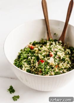 A bowl of quinoa tabbouleh salad with wooden serving spoons