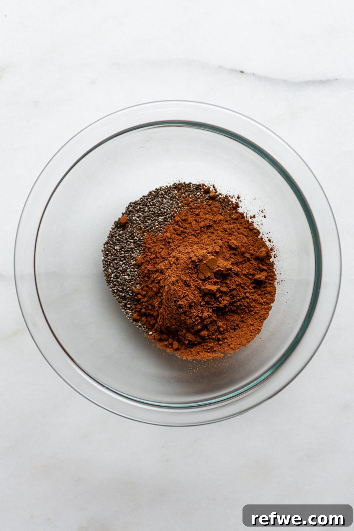 Decadent Chocolate Chia Pudding 4 A clear mixing bowl containing dry chia seeds and cocoa powder, perfectly prepped for the next step in making chocolate chia pudding.