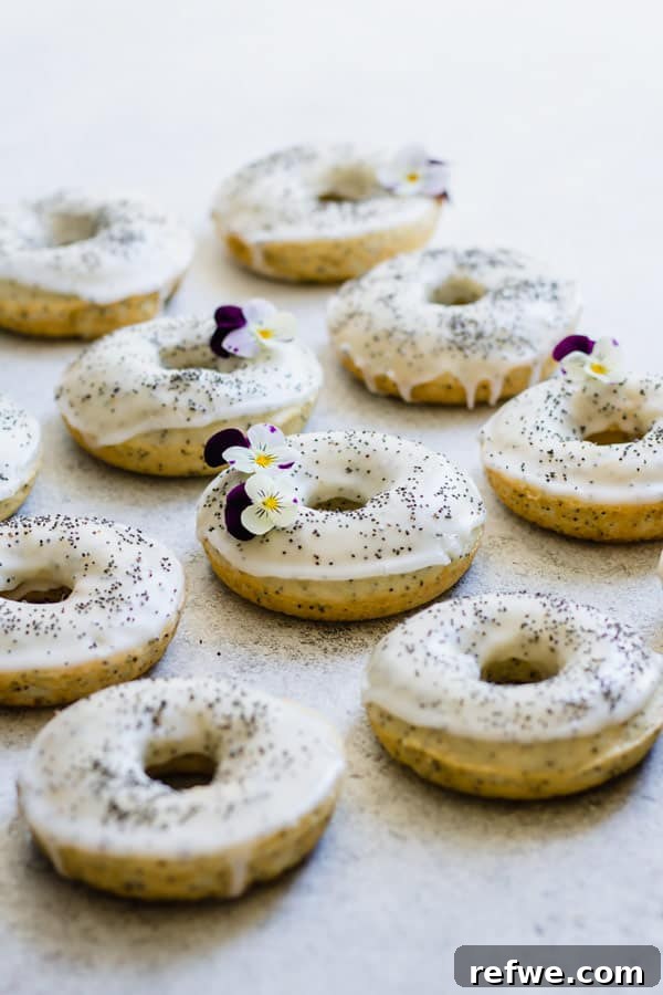 Stack of glazed vegan lemon poppy seed donuts on a plate