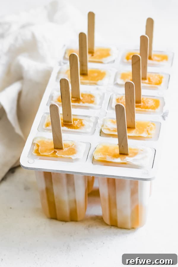 Creamy Mango Lassi Pops 3 A close-up shot of a popsicle mold filled with partially frozen mango lassi mixture, showcasing the beautiful layered effect, ready for the freezer.