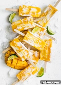 Stacked vegan mango lassi popsicles, showcasing their creamy, layered texture and vibrant yellow color, inviting a refreshing bite.