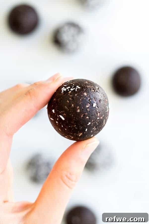 Chocolate Macaroon Power Bites 4 Stack of chocolate macaroon energy balls, garnished with extra shredded coconut, on a wooden board.