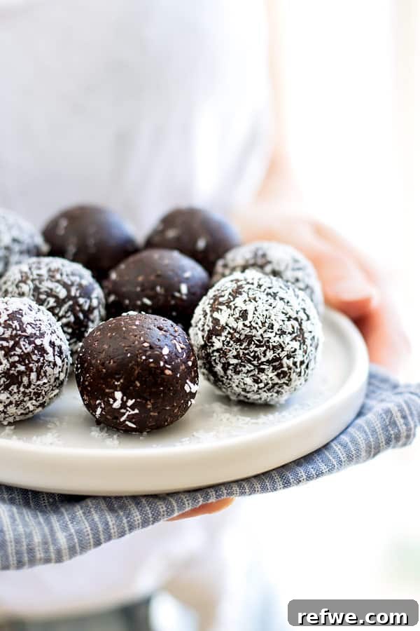 Chocolate Macaroon Power Bites 5 Four chocolate macaroon energy balls stacked neatly on a white ceramic plate.