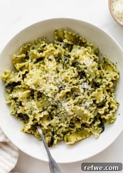 Pesto pasta in a bowl with a fork in it, tempting and ready to be enjoyed