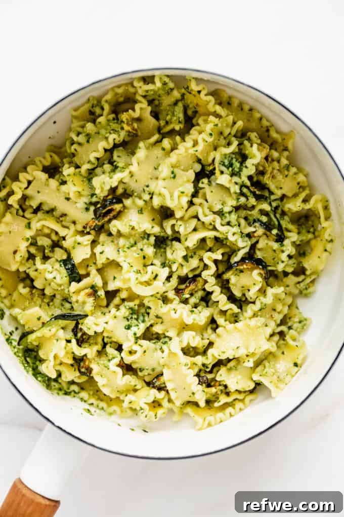 Zesty Pesto Veggie Medley 7 Noodles thoroughly coated with vibrant green pesto in a white pot, ready for the final touches