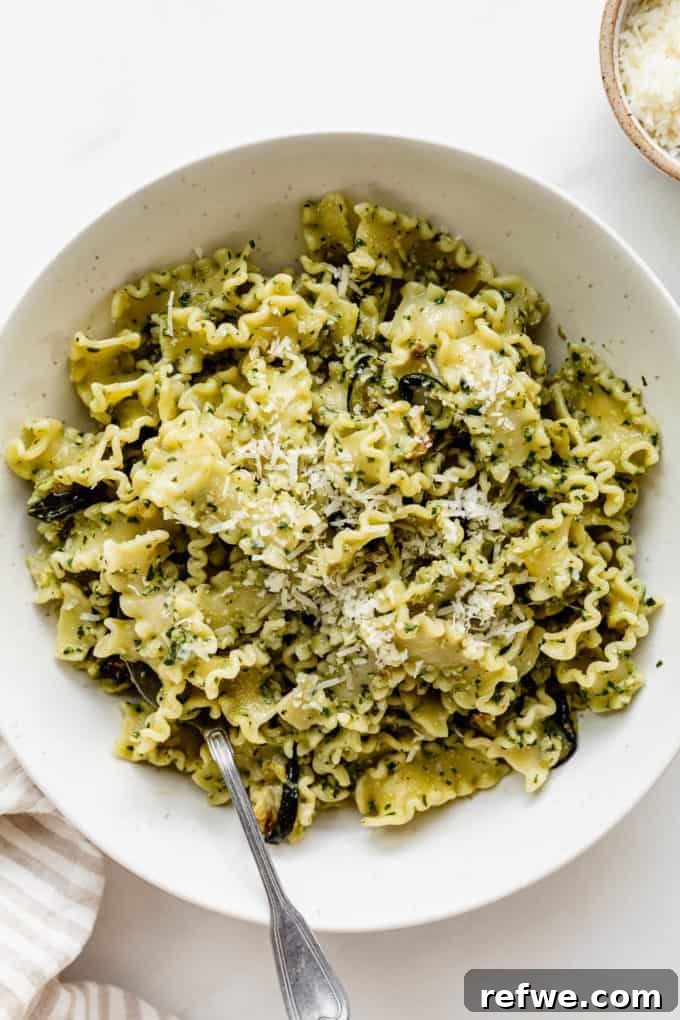 Zesty Pesto Veggie Medley 8 A close-up of a serving of pesto pasta in a white bowl with a fork, ready to be enjoyed