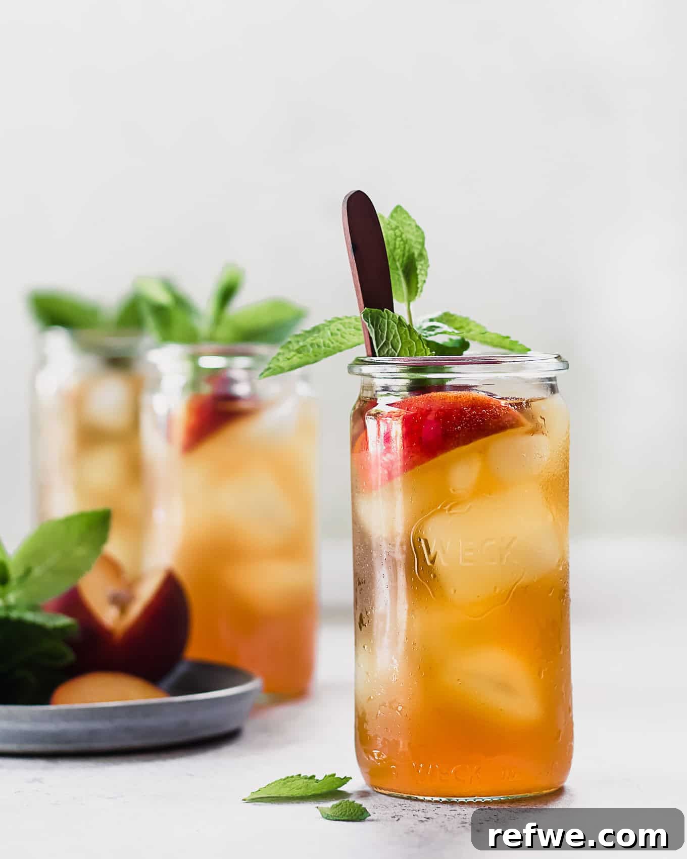 Peach Cold Brew Refresher 2 A cup of cold brew peach iced tea with peaches and mint garnish.