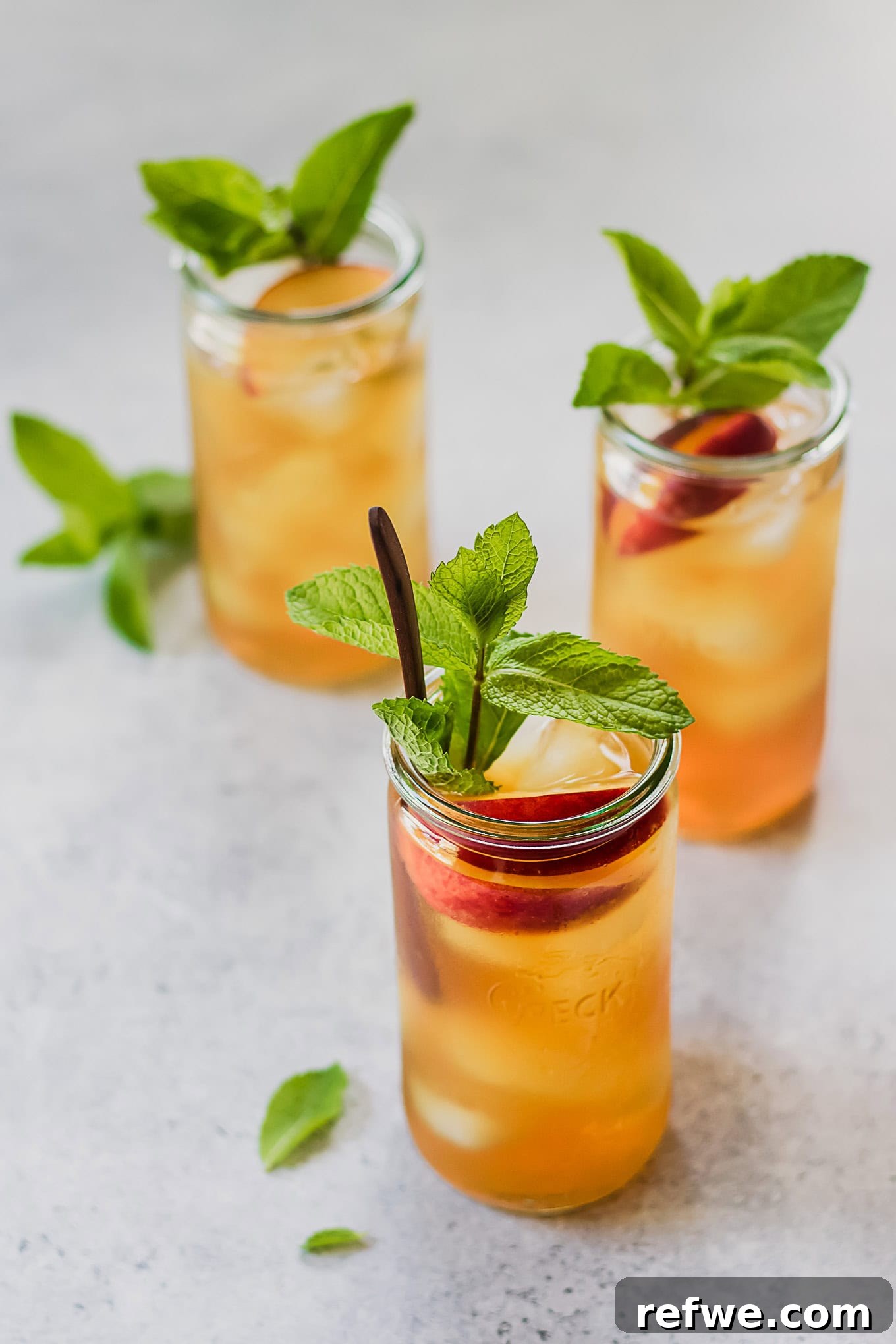 Peach Cold Brew Refresher 3 Three jars of peach iced tea garnished with fresh mint sprigs.