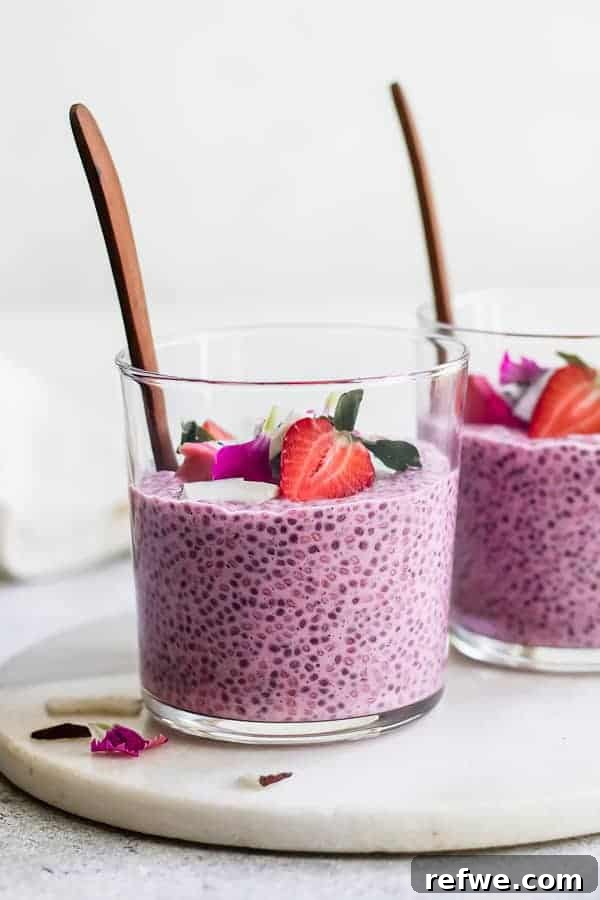 Close-up of a single glass jar of Strawberry Dragonfruit Chia Pudding with lime zest and fresh strawberry slices.