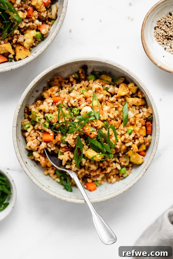 Savory Vegan Tofu Fried Rice 2 A bowl of vibrant vegan fried rice with a side of sesame seeds, ready to be served.