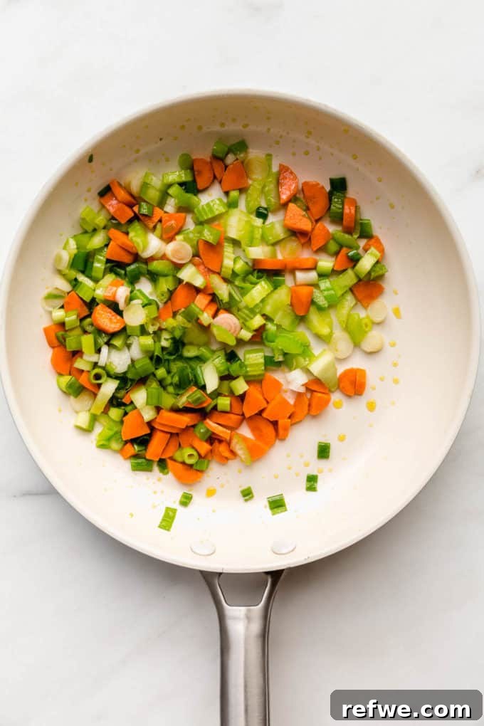 Savory Vegan Tofu Fried Rice 4 Freshly chopped green onions, celery, and carrots glistening in a white pan, ready for stir-frying.