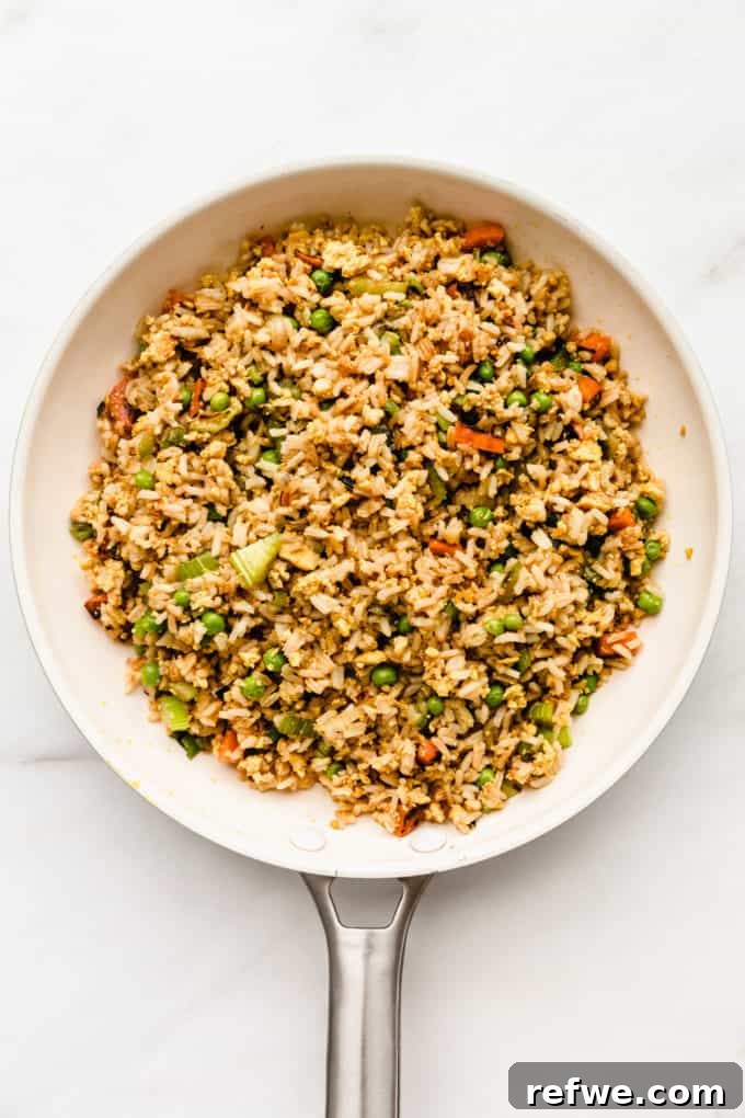 Savory Vegan Tofu Fried Rice 6 A close-up of vegan fried rice in a white pan, showing the golden-brown crispiness developing at the bottom.