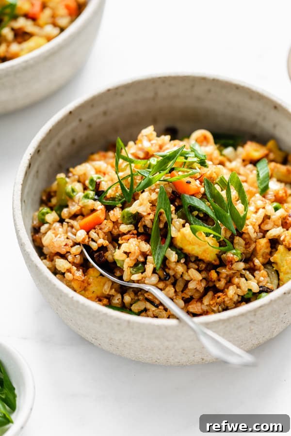 Savory Vegan Tofu Fried Rice 8 A beautifully presented bowl of vegan fried rice with a spoon, ready to be enjoyed.