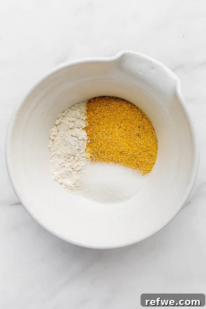 Plant-Based Cornbread 4 A white bowl filled with dry ingredients for vegan cornbread, including flour, cornmeal, and sugar, ready to be mixed.