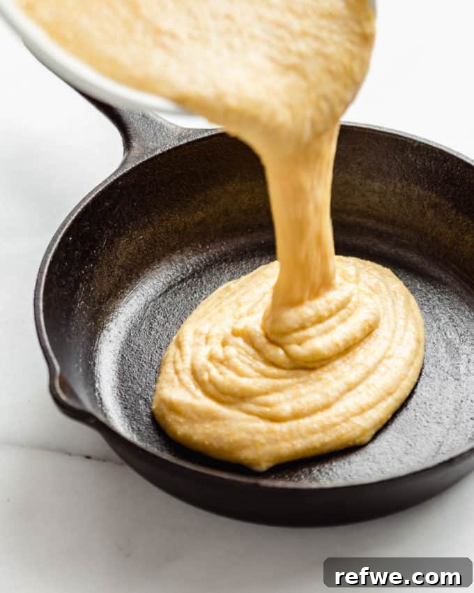 Plant-Based Cornbread 7 Smooth vegan cornbread batter being gracefully poured into a perfectly greased cast iron skillet, ready for baking.