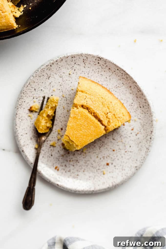 Plant-Based Cornbread 10 A perfectly baked slice of moist vegan cornbread, displaying its tender crumb and golden crust, resting invitingly on a white ceramic plate.