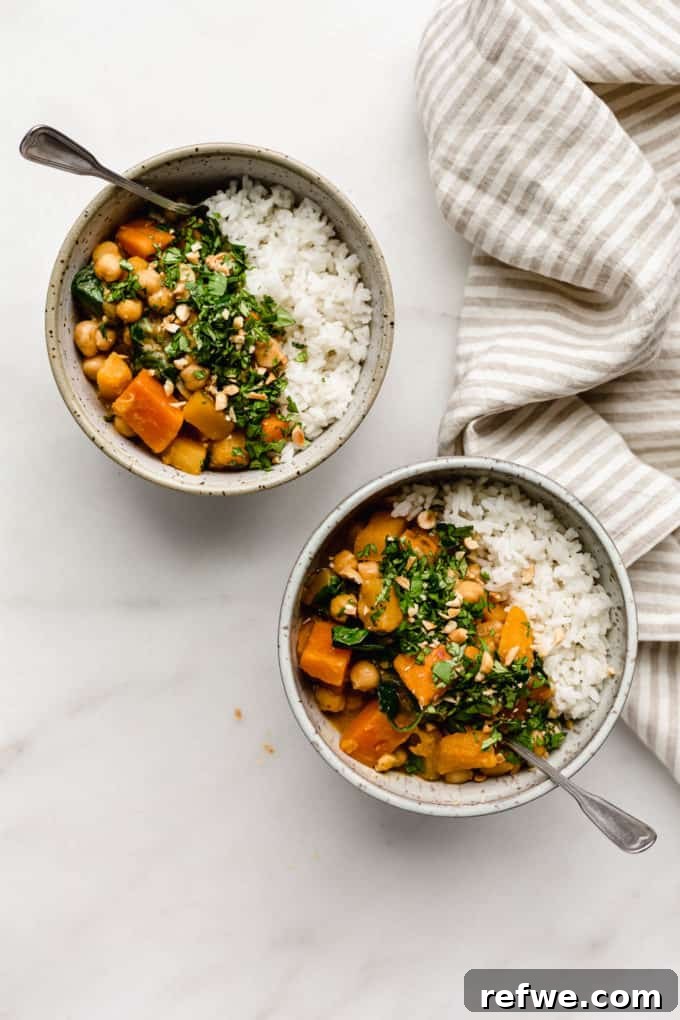 Hearty Slow Cooker Chickpea Pumpkin Curry 5 Two cozy bowls of chickpea pumpkin curry and rice sit on a table with a striped napkin, inviting you to dig in.