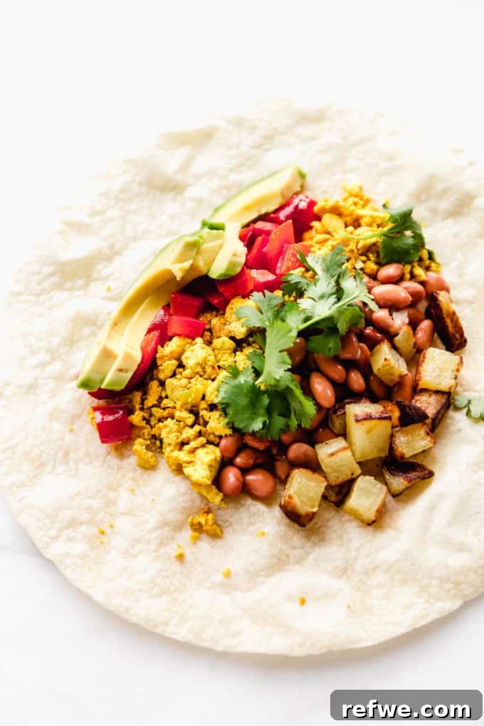Plant-Powered Breakfast Wrap 5 A tortilla filled with potatoes, beans, tofu, peppers, and avocado, ready to be rolled