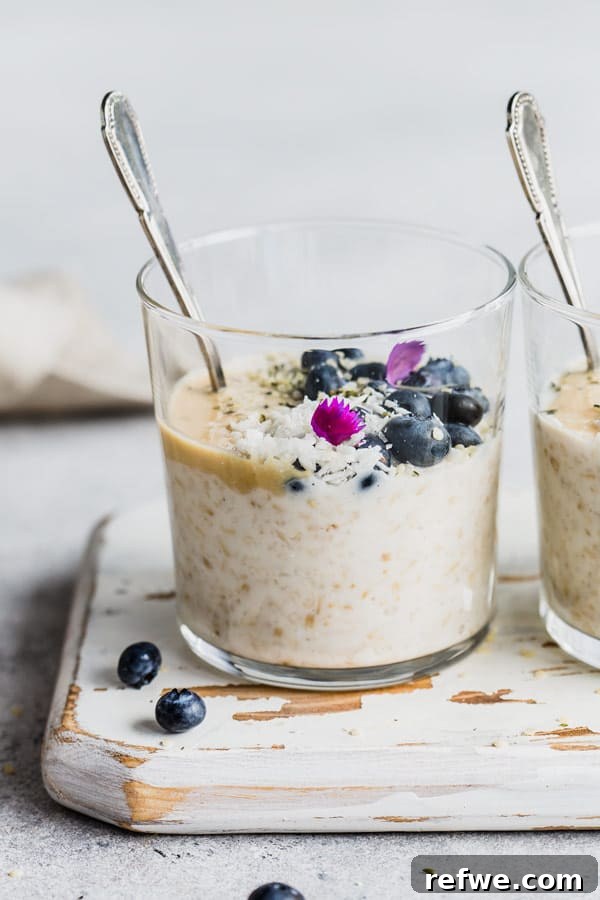 Effortless Overnight Steel Cut Oats 4 A simple yet inviting cup of steel cut oats with a spoon, resting on a clean white wooden board, highlighting its wholesome appeal.