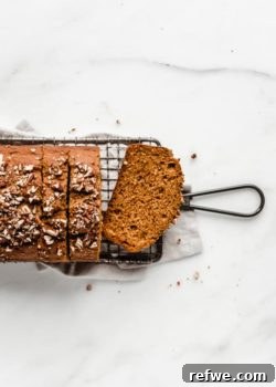 A pumpkin bread sliced on a cooling rack, showing its inviting texture and golden color.
