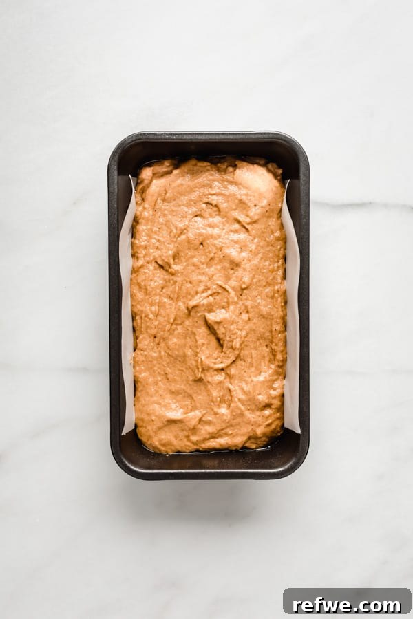 Wholesome Spiced Pumpkin Bread 6 Pumpkin bread batter meticulously poured into a parchment-lined loaf pan, ready for baking.