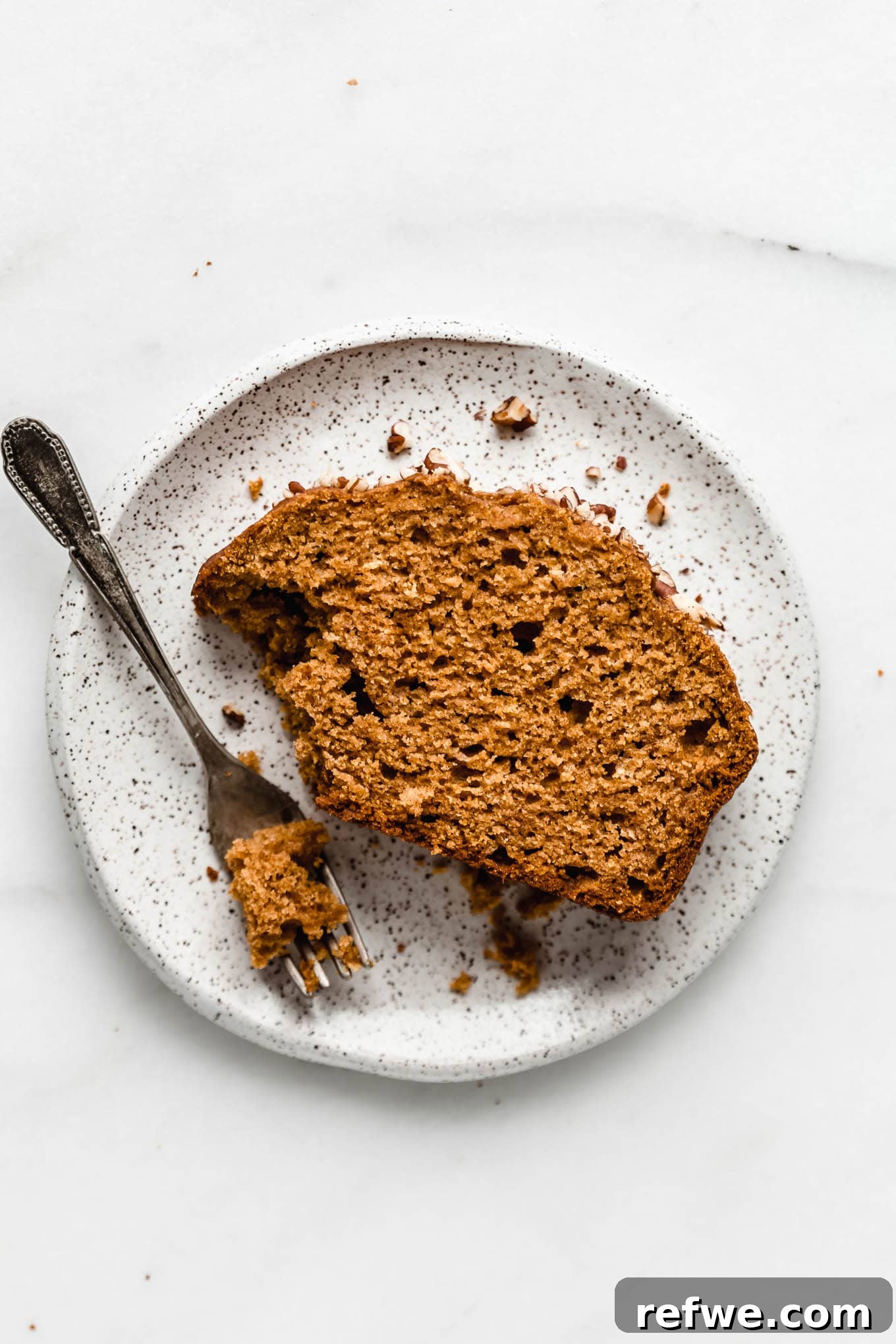 Wholesome Spiced Pumpkin Bread 9 A perfectly sliced piece of maple pumpkin bread on a white speckled plate, highlighting its moist texture.