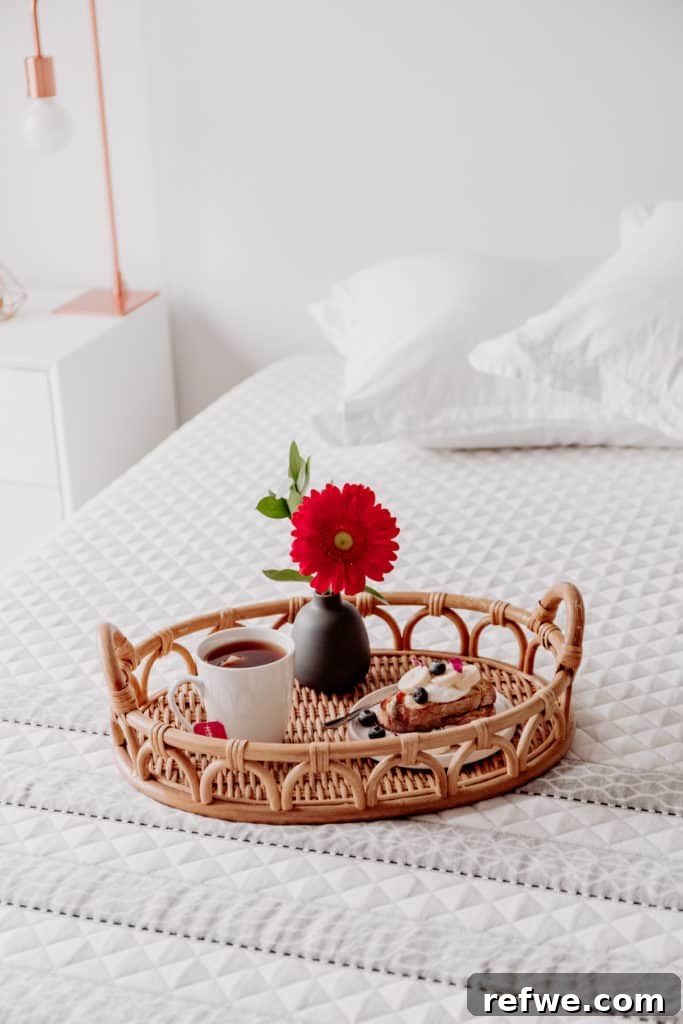 Indulgent Mornings Breakfast in Bed Secrets 2 A charming breakfast in bed setup featuring French toast, tea, and a flower on a rattan tray, placed on a soft, inviting bed.